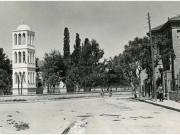 Η κατάφυτη αυλή του παλαιού ναού του Αγ. Νικολάου με το μεταπολεμικό καμπαναριό. Δεξιά στο διώροφο κτίριο στεγαζόταν μέχρι το 1957 το Δημαρχείο της Λάρισας. Φωτογραφία από επιστολικό δελτάριο του Νικ. Στουρνάρα. 1955 περίπου. Αρχείο Φωτοθήκης Λάρισας