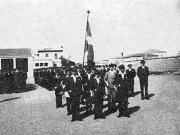  Οι μαθητές του Γυμνασίου συντεταγμένοι στο σχολικό Γυμναστήριο για την πομπή της εορτής του Αγίου Αχιλλίου του 1933. Στο βάθος το υπόστεγο και τα αποδυτήρια και πίσω το αρχοντικό του Λεωνίδα Μπέρτολη. Από το αρχείο του Γιώργου Ζιαζιά
