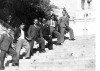 Μια ομάδα έξι καλοντυμένων νεαρών φωτογραφίζεται συμμετρικά με την ίδια στάση στα σκαλοπάτια του Αγ. Αχιλλίου. Προπολεμική φωτογραφία.