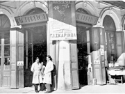 Το παντοπωλείο του Νικολάου Πράττου, στη γωνία των οδών Πανός  και των Εξ (Κύπρου). Αριστερά ο γιος του καταστηματάρχη Μιχαήλ Πράττος. «Πανλαρισαϊκόν Φωτο-Κ. Ρούμσον». 1933.