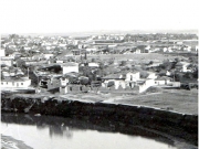 Ο Ξενώνας των Ζαρκινών, αργότερα υφαντουργείο Γ. Πατσάλη,  κοντά στη δεξιά όχθη του Πηνειού, σε ερειπιώδη κατάσταση  μετά τον πυρκαγιά του 1925. Λεπτομέρεια από επιστολικό δελτάριο  του Νικ. Κουρτίδη (Nicourt). 1935 περίπου