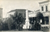 Η βορειοδυτική γωνία της Κεντρικής πλατείας (Θέμιδος). Πίσω προβάλλει το ξενοδοχείο &quot;Όλυμπος&quot; , το φαρμακείο Νικ. Ζησιάδου και το ξενοδοχείο &quot;Το Στέμμα&quot;. Επιστολικό δελτάριο άγνωστου εκδότη. 1933 περίπου. Αρχείο Φωτοθήκης Λάρισας