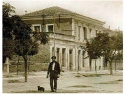 Το κτίριο του Ταχυδρομείου και Τηλεγραφείου στη γωνία των οδών Μουσών (Παπακυριαζή) και Αχιλλέως (Παναγούλη) στην πλατεία Ταχυδρομείου. Λεπτομέρεια επιστολικού δελταρίου του Fr. Caloutas από τη Σύρο. Αρχείο Φωτοθήκης.