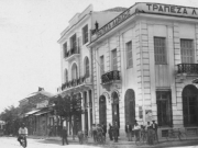 Η γωνία των οδών Μακεδονίας (Βενιζέλου) και Βασ. Σοφίας (Παπαναστασίου). Από δεξιά, το κτίριο της Τράπεζας Λαρίσης, το μέγαρο Αλεξάνδρου και ο τρούλος του τουρκικού λουτρού (Χαμάμ). Επιστολικό δελτάριο Ιω. Κουμουνδούρου. 1933 περίπου. Αρχείο Φωτοθήκης Λάρισας.