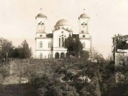 Ο προπολεμικός ναός του Αγ. Αχιλλίου και η μεγάλη πέτρινη σκάλα (κρυμμένη πίσω από φυλλωσιές δένδρων) στη δεξιά όχθη του Πηνειού. Φωτογραφία του 1938 περίπου. Από το αρχείο του Θανάση Μπετχαβέ