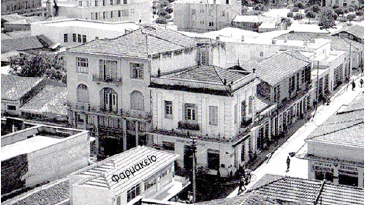 Το Φαρμακείο Καραθάνου στη γωνία των οδών Βενιζέλου  και Παπαναστασίου, απέναντι από το παλαιό κτίριο της Τραπέζης Λαρίσης.  Το βέλος υποδεικνύει μία από τις θέσεις που στεγάσθηκε το φαρμακείο.  Λεπτομέρεια από μεταπολεμική φωτογραφία του Τάκη Τλούπα.